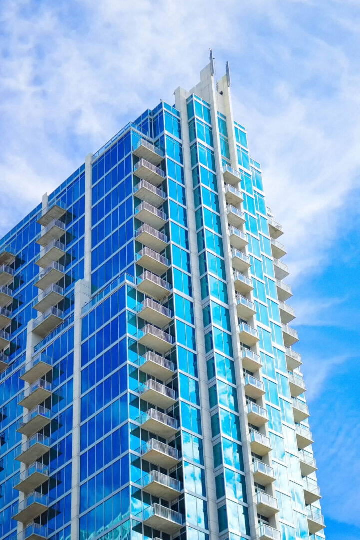A tall blue building with many windows on the outside.